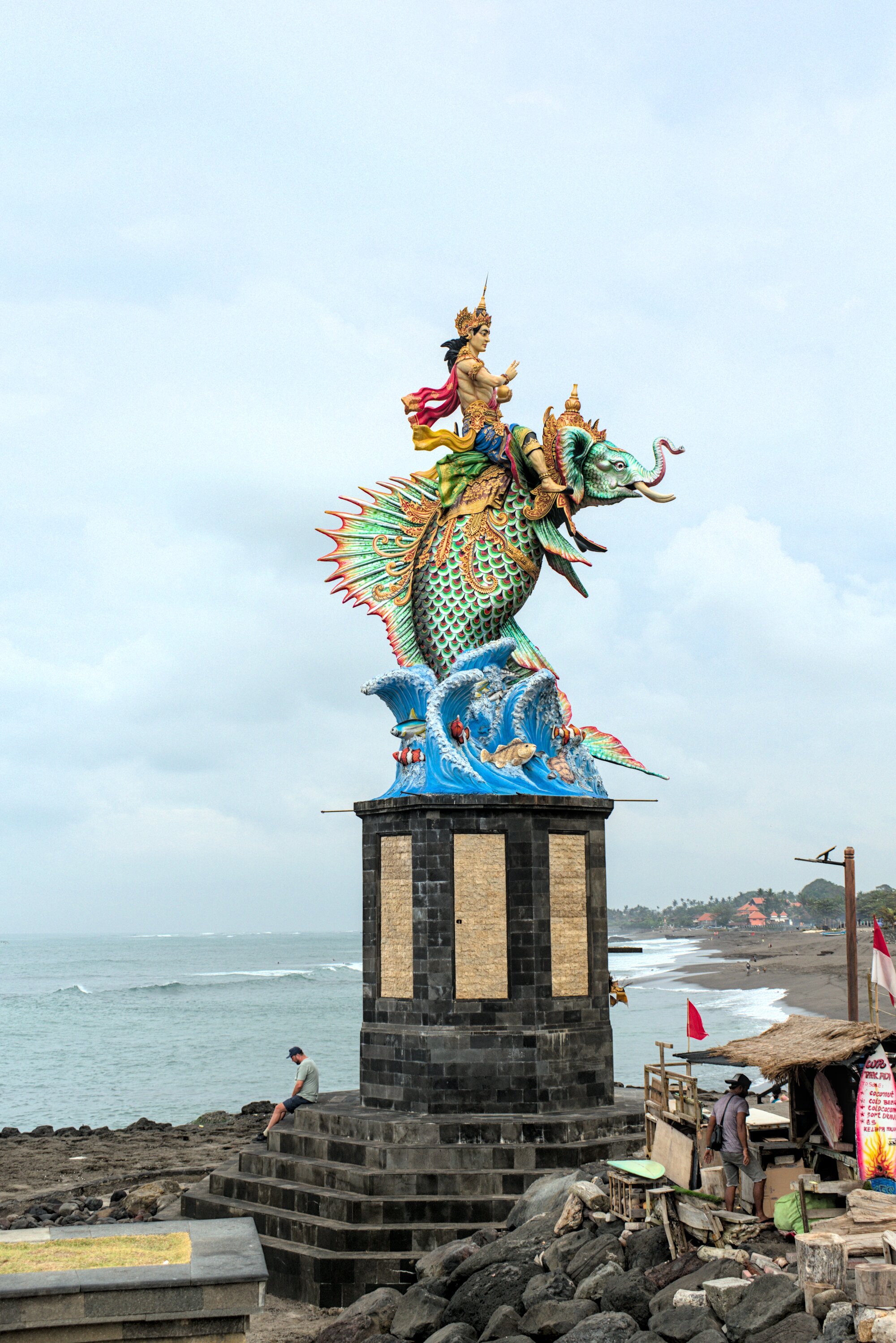 Giant gilded statue on a beach, presumably a Hindu deity.
