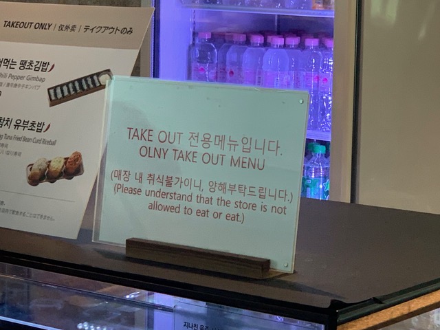 A sign in Korean and English. The English portion reads: OLNY TAKE OUT MENU / Please understand that the store is not allowed to eat or eat.
